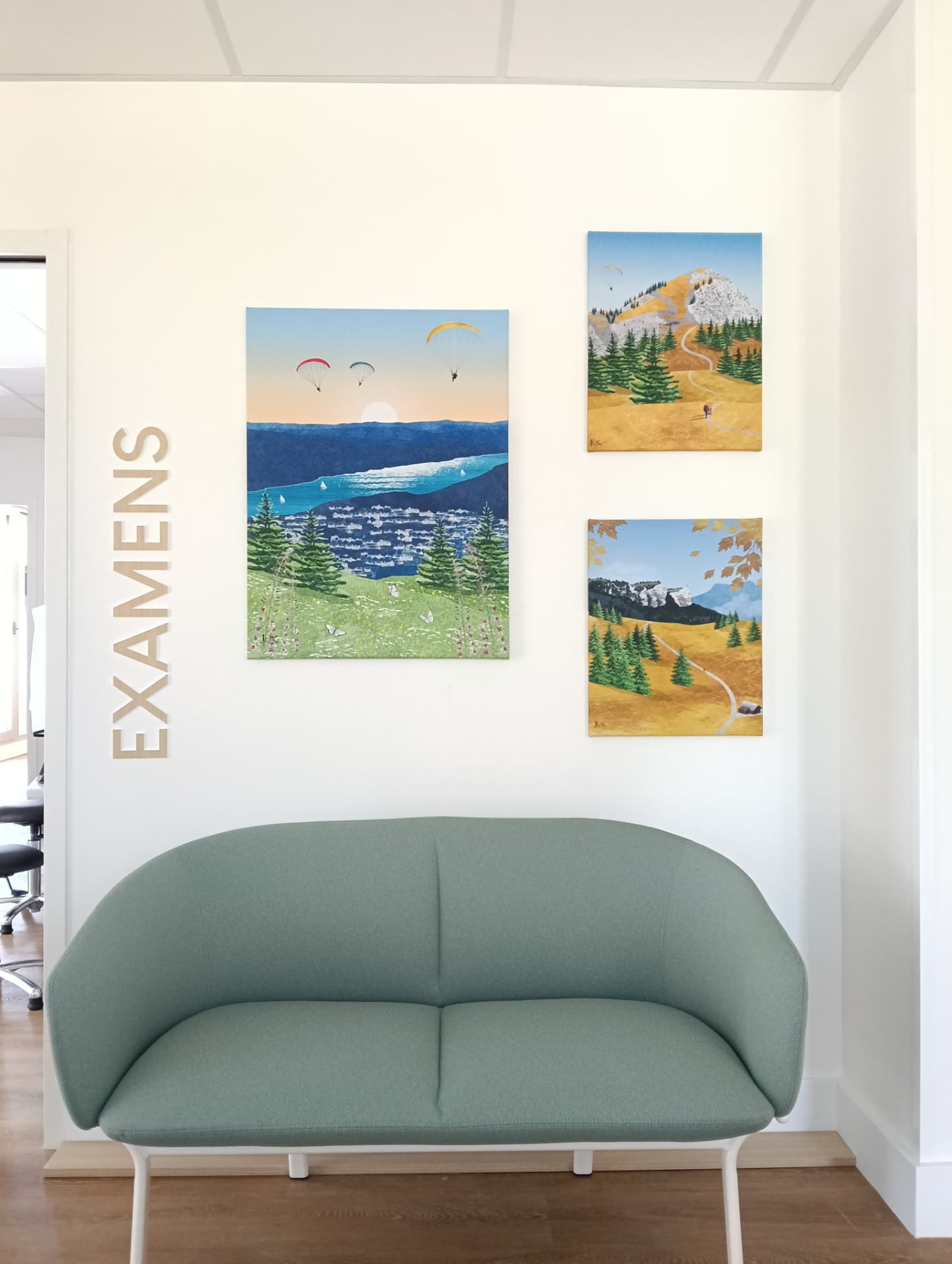 Fixation murale d'un ensemble de trois toiles décoratives paysages au-dessus d'une banquette dans un espace d'accueil professionnel à Chambéry